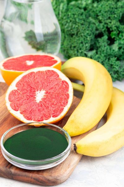 Ingredients for green smoothie with kale, chlorella, banana and grapefruit detox drink, vertical